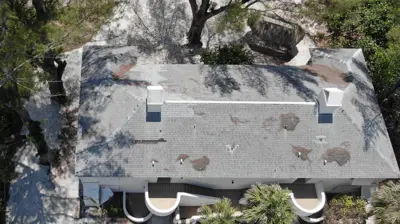 Vista aérea de una vivienda en Sarasota, Florida, que muestra signos de una instalación deficiente del tejado, incluyendo tejas desiguales y cabezas de clavos oxidadas.