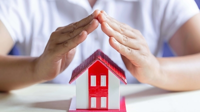 manos encima de una casa de juguete