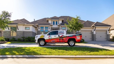 El camión de Mighty Dog Roofing aparcado junto a una propiedad con tejado nuevo