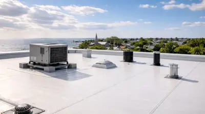 Tejado plano comercial con membrana EPDM y unidad de climatización con vistas a una ciudad costera de Rhode Island bajo un cielo despejado.