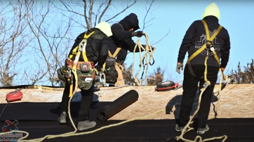 Tres personas de pie sobre un tejado con equipo de seguridad