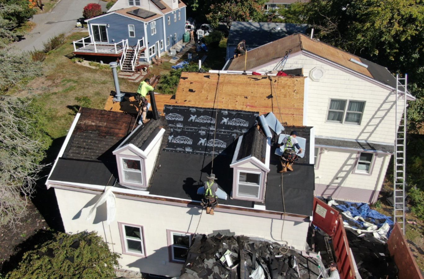 Técnicos de Mighty Dog Roofing instalando componentes de tejado en Burlington, MA, destacando las ventajas del servicio de una empresa de tejados de confianza.