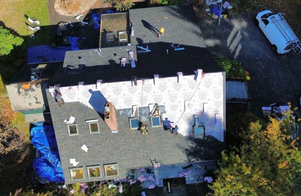 Un profesional de Mighty Dog Roofing realizando una inspección del techo en Groton, MA para las necesidades de servicio residencial.