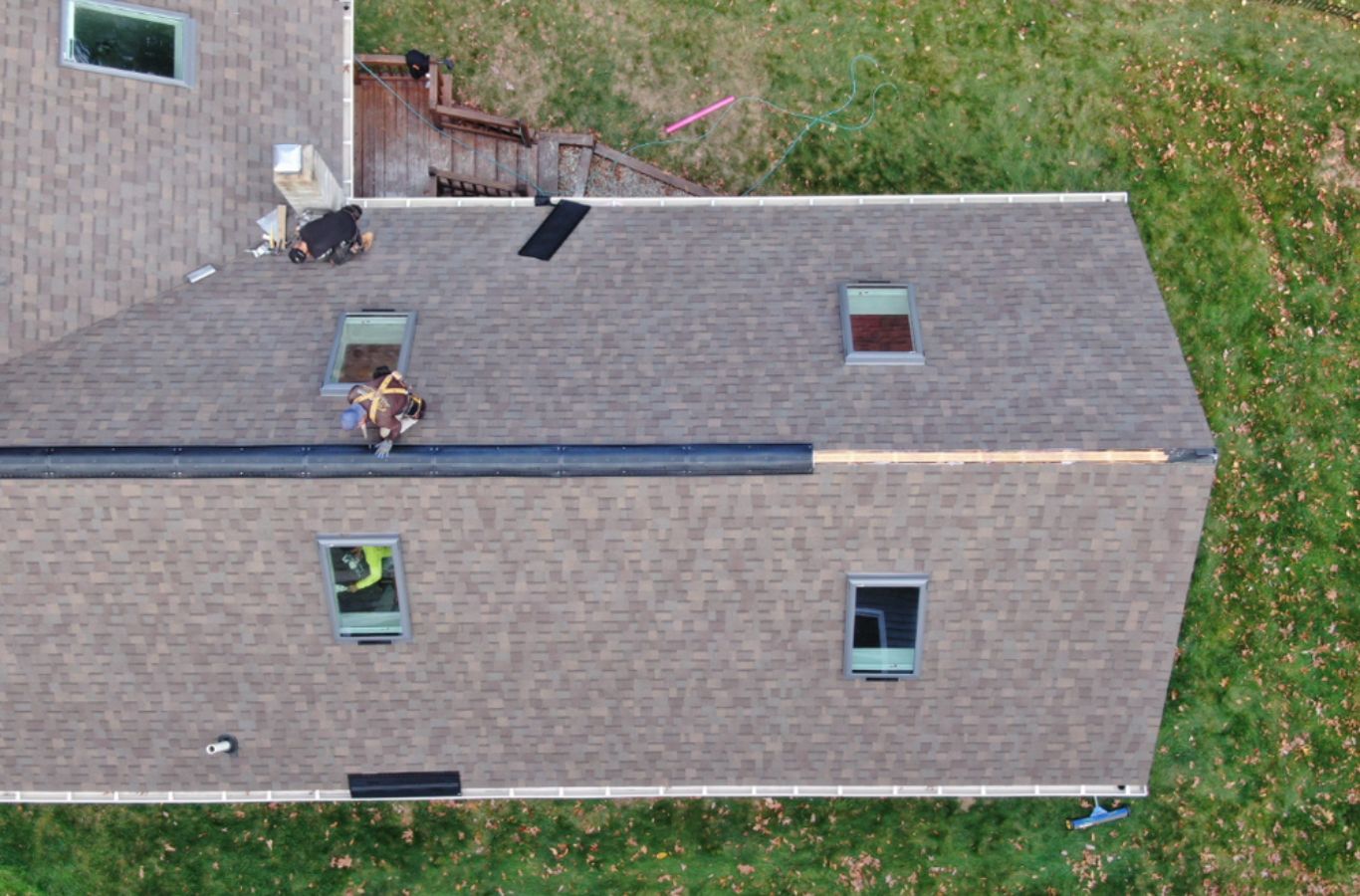 Un técnico Mighty Dog Roofing asegurar paneles de revestimiento en Woburn, MA con herramientas de precisión y mano de obra experta.