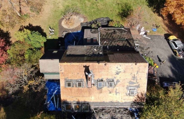 Equipo de techado de Mighty Dog Roofing instalando tejas en un techo de Groton, MA con cuidado experto. Roofing Company cerca de mí.