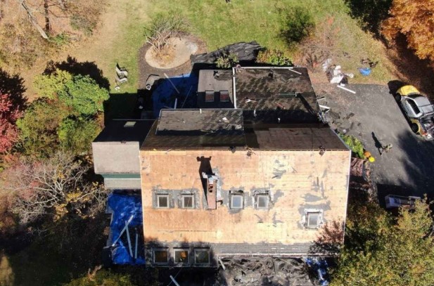 Un techador sustituye las tejas de asfalto de una vivienda de Dunstable, MA, durante una visita de mantenimiento.
